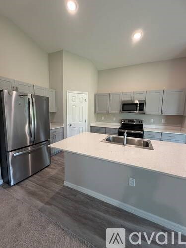 A kitchen with a stainless steel refrigerator and a sink.