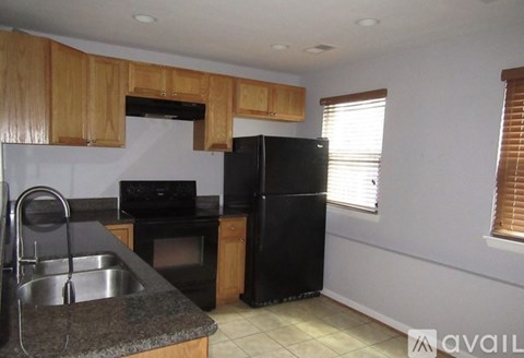 A kitchen with black appliances and wooden cabinets.