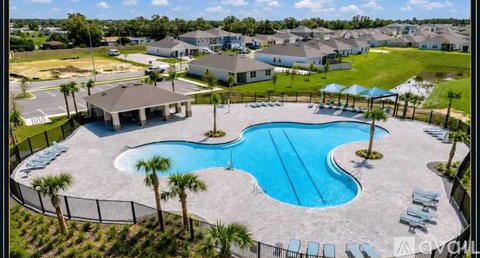 A large outdoor swimming pool surrounded by a fence and lounge chairs.