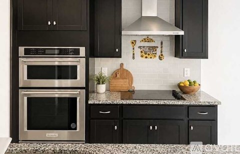 A modern kitchen with black cabinets and a stainless steel oven.