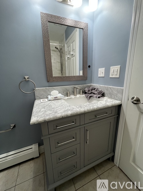 A bathroom with a marble countertop and a mirror above it.