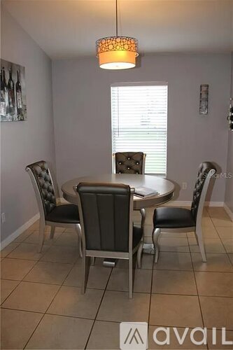 A dining room with a round table and chairs.