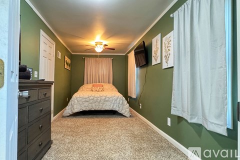 A bedroom with a bed, dresser, and window.
