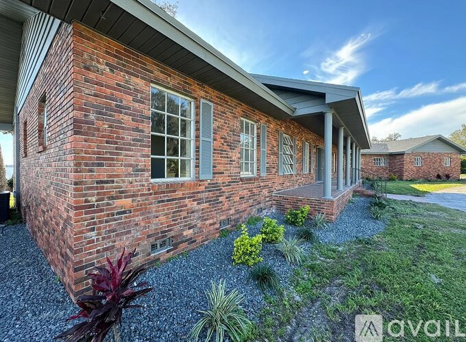 A brick house with a gravel area in front.