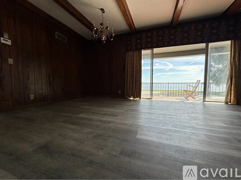 A spacious room with wooden walls and a large window overlooking a balcony.