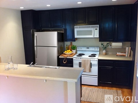 A kitchen with black cabinets and a white stove top oven.
