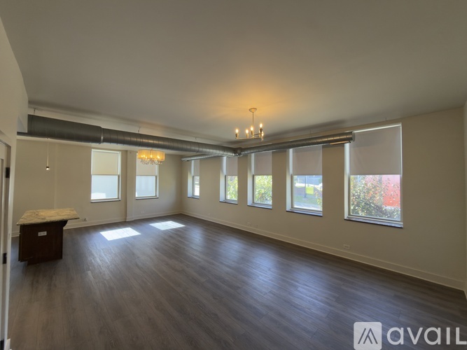 A spacious room with wooden floors and large windows.