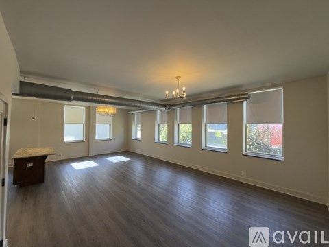 A spacious room with wooden floors and large windows.