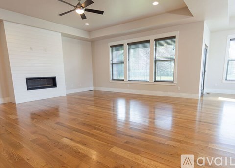 A spacious room with a fireplace and wooden flooring.