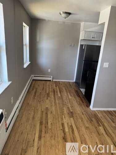 A room with wooden flooring and a window on the left side.