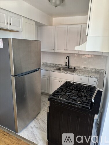 A kitchen with a stainless steel refrigerator and a black stove top.