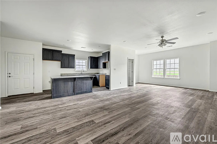 A spacious room with wooden flooring and a ceiling fan.