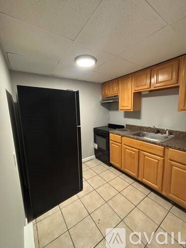 A kitchen with wooden cabinets and a black refrigerator.