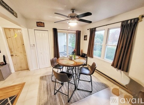 A dining room with a table set for four and a ceiling fan.