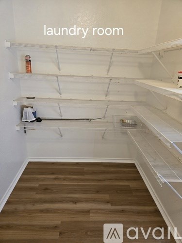 A laundry room with wooden floors and white walls.