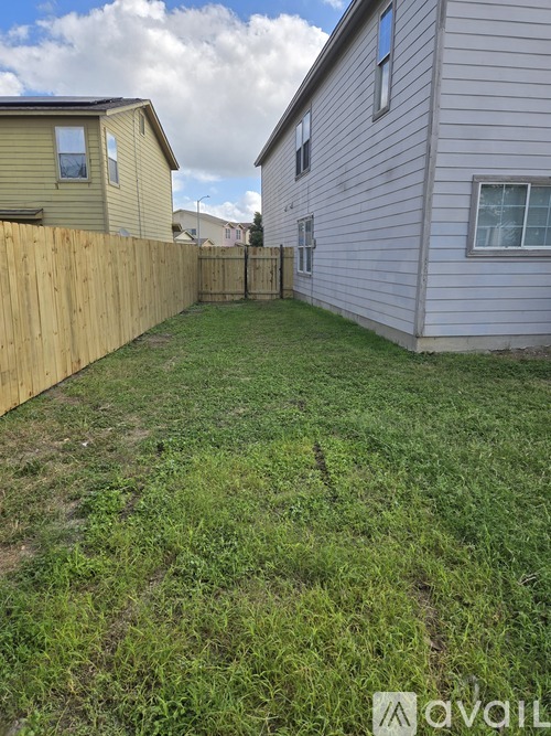 A backyard with a wooden fence and a grassy area.