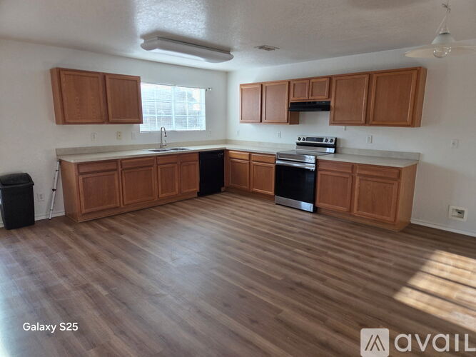 A kitchen with wooden cabinets and a black trash can.