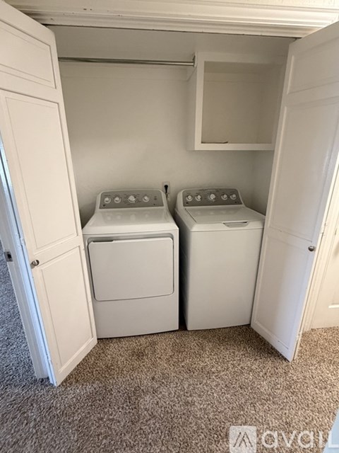 Two white front loading washing machines in a small laundry room.