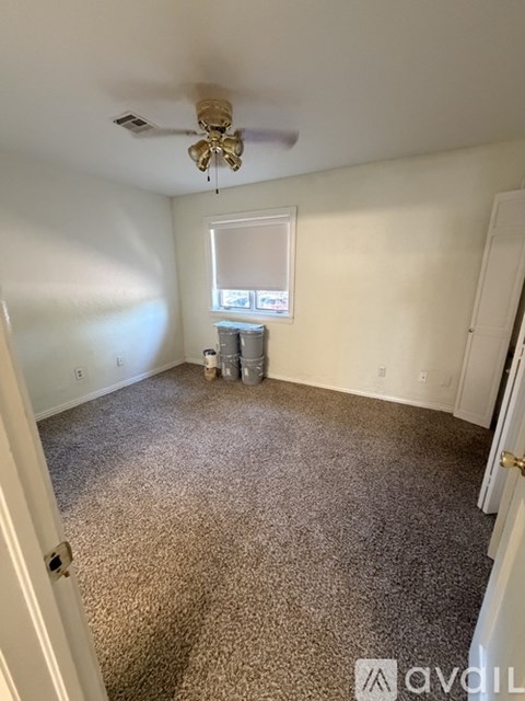 A room with a ceiling fan and carpeted floor.