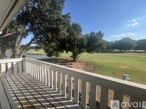 A balcony with a view of a green field and trees.