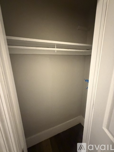 A white closet with a shelf and a blue tag on the door.