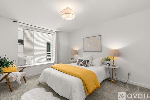 A bedroom with a white bed and a yellow throw blanket.
