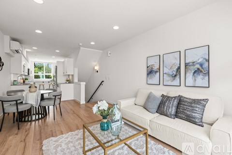 A living room with a white couch, a coffee table, and a dining table with chairs.