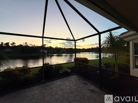A balcony with a view of a lake and trees at sunset.