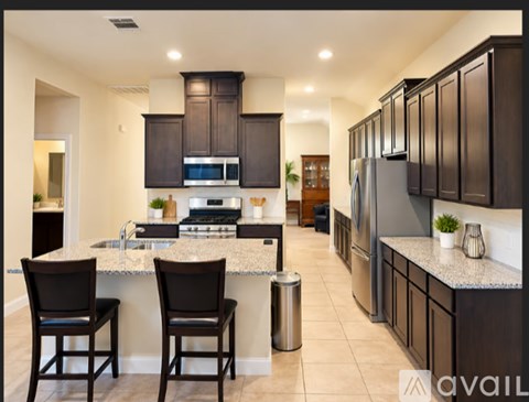 A modern kitchen with dark brown cabinets and a granite countertop.