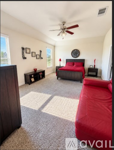 A bedroom with a red couch and a bed with red bedding.