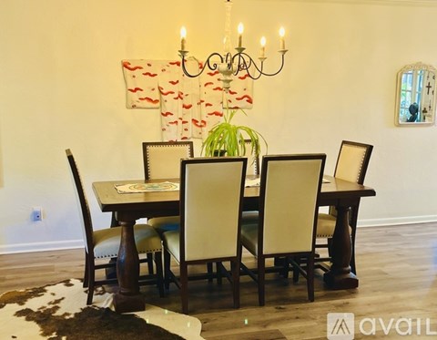 A dining room with a table set for four and a chandelier.