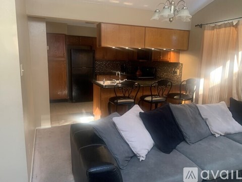 A living room with a grey couch and a kitchen area in the background.