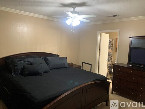 A bedroom with a bed, dresser, and television.