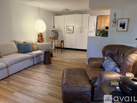 A living room with a brown leather couch and a white sofa.