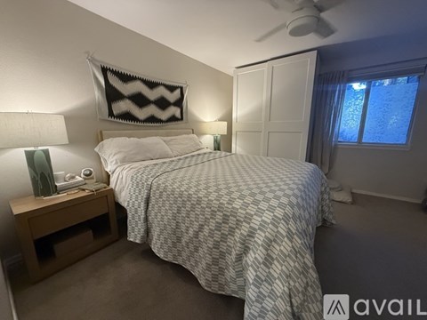 A bedroom with a bed, nightstand, and window.