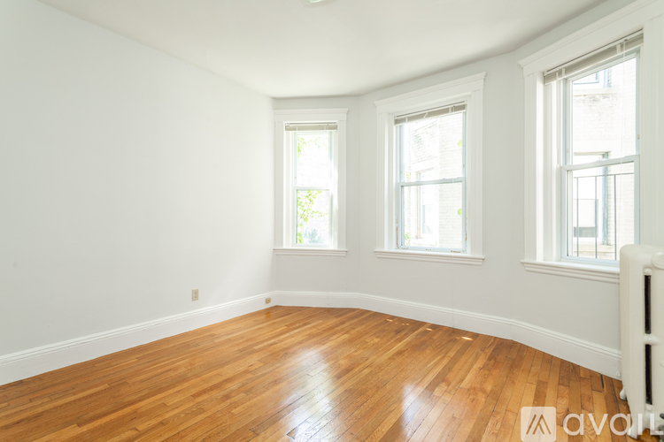 A room with wooden floors and three windows.