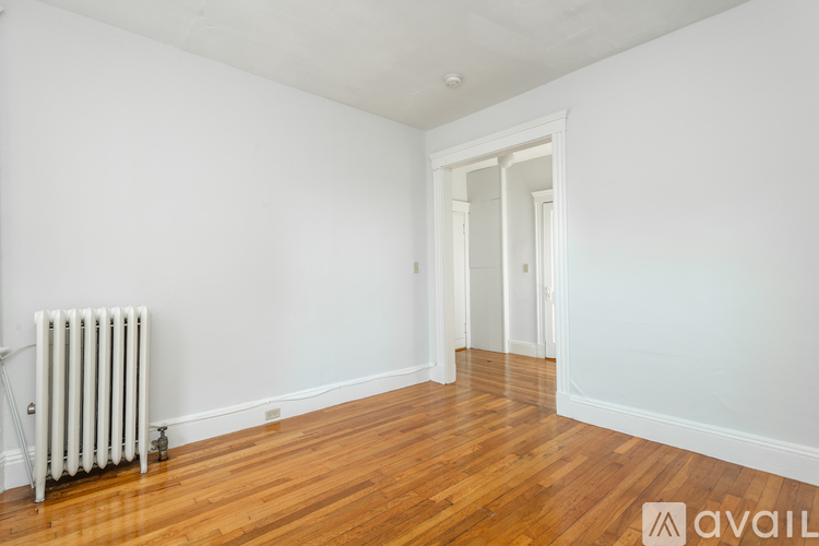 A room with a white wall and a white radiator on the floor.
