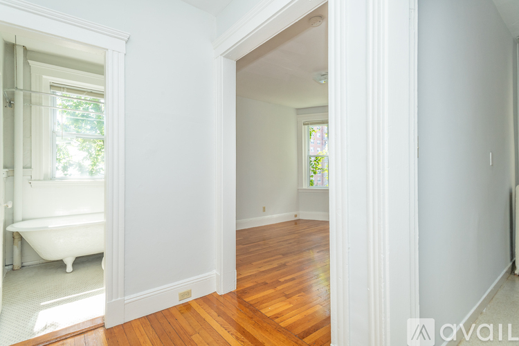 A white bathroom with a wooden floor and a window.