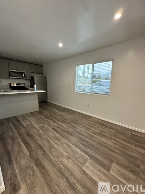 A room with wooden flooring and a kitchen area with a microwave and oven.