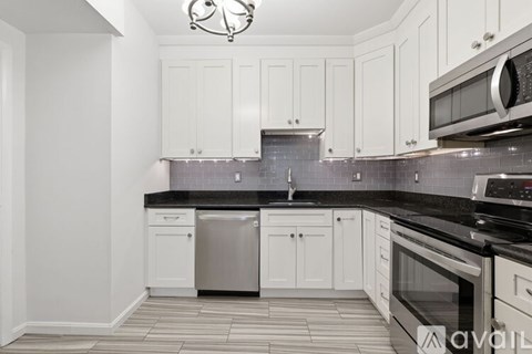 A kitchen with white cabinets and black countertops.