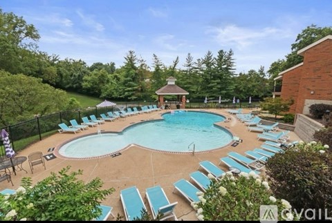 A pool surrounded by lounge chairs and umbrellas with a gazebo in the background.