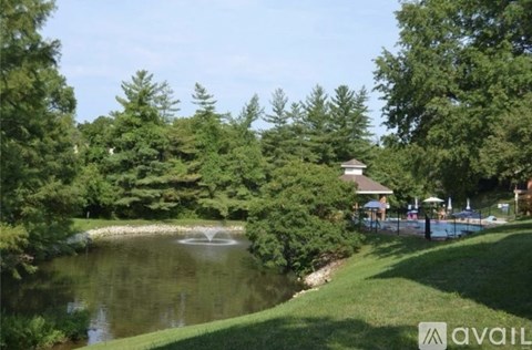 A pond with a fountain in the middle of it surrounded by trees.