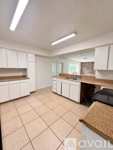 A kitchen with white cabinets and a tiled floor.
