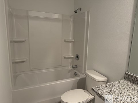 A white toilet sits next to a bathtub in a bathroom.