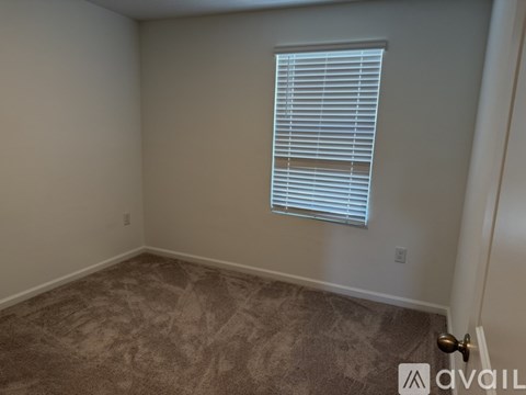 A room with a carpeted floor and a window with blinds.
