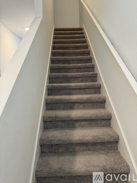A staircase with a carpeted runner and white walls.