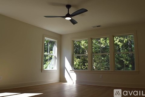 A room with a fan and windows overlooking trees.