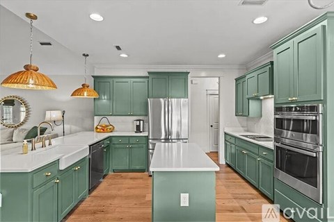 A kitchen with green cabinets and a white countertop.
