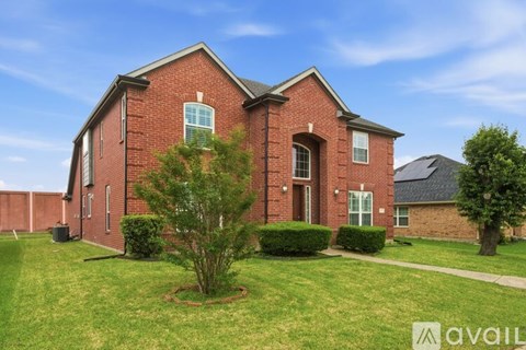 A red brick house with a green lawn in front.