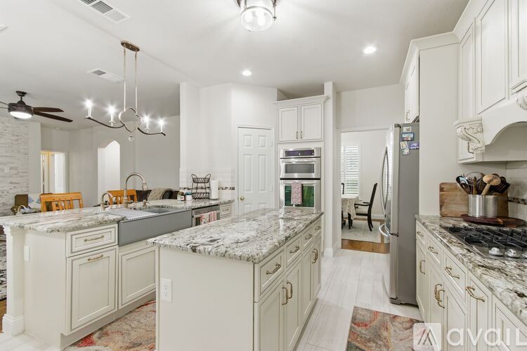 A kitchen with white cabinets and a marble countertop.